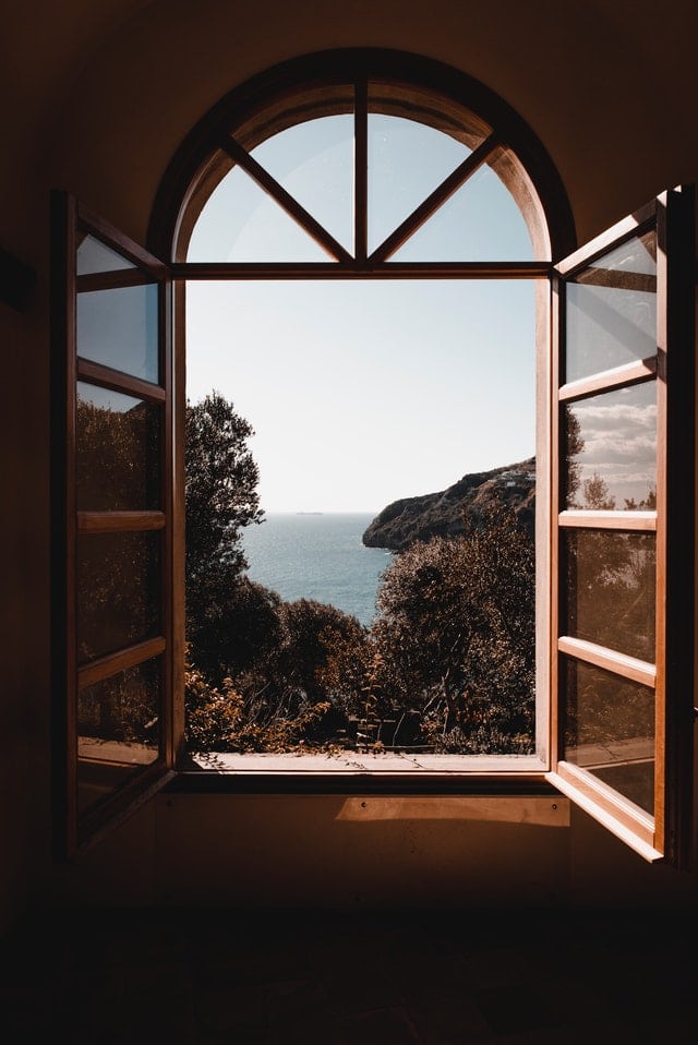 Open arched window with a scenic view of the ocean and trees